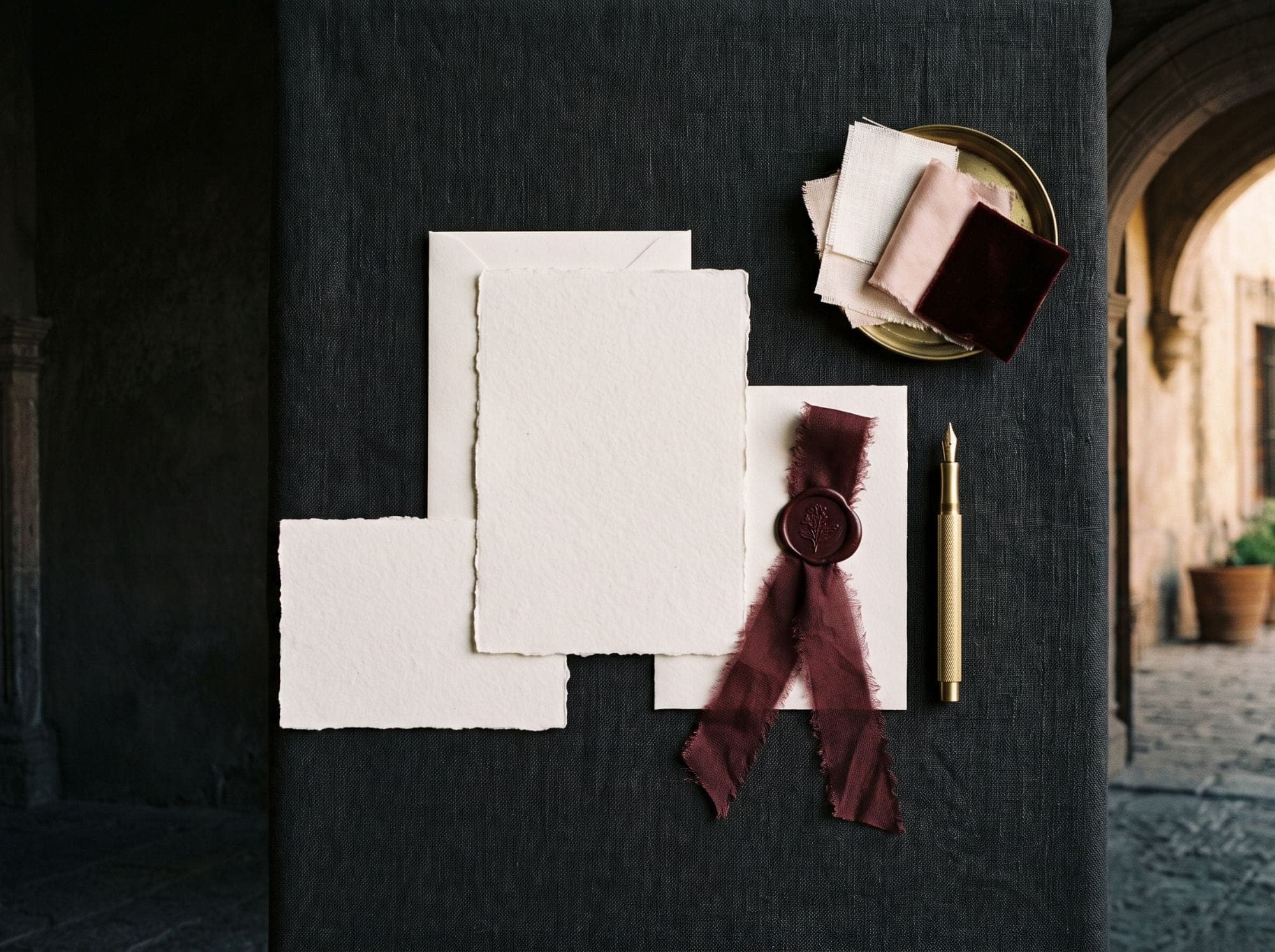 Papelería de boda con sello de lacre vino sobre lino negro